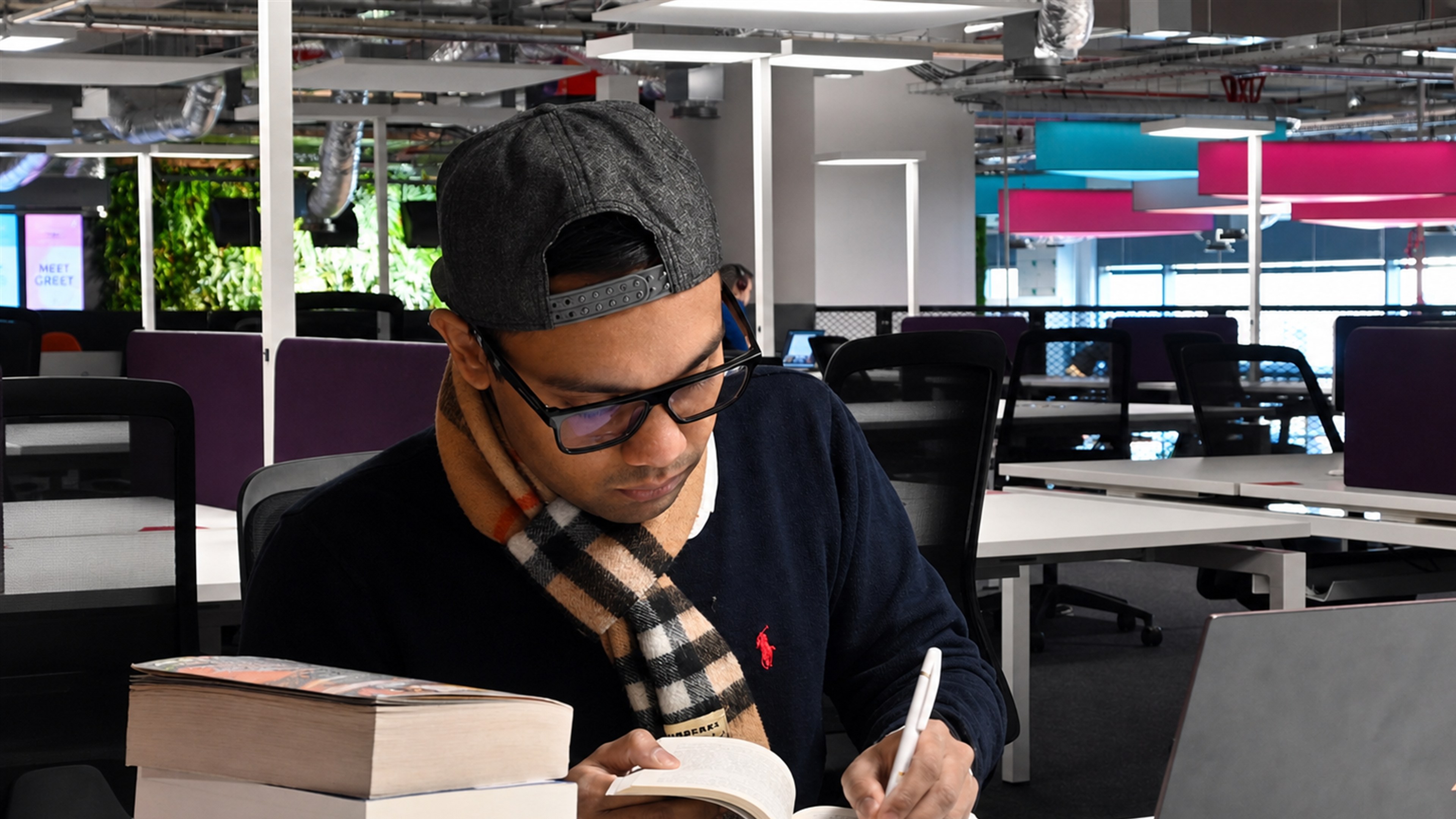 Farabi writing at Plexal, with books beside him